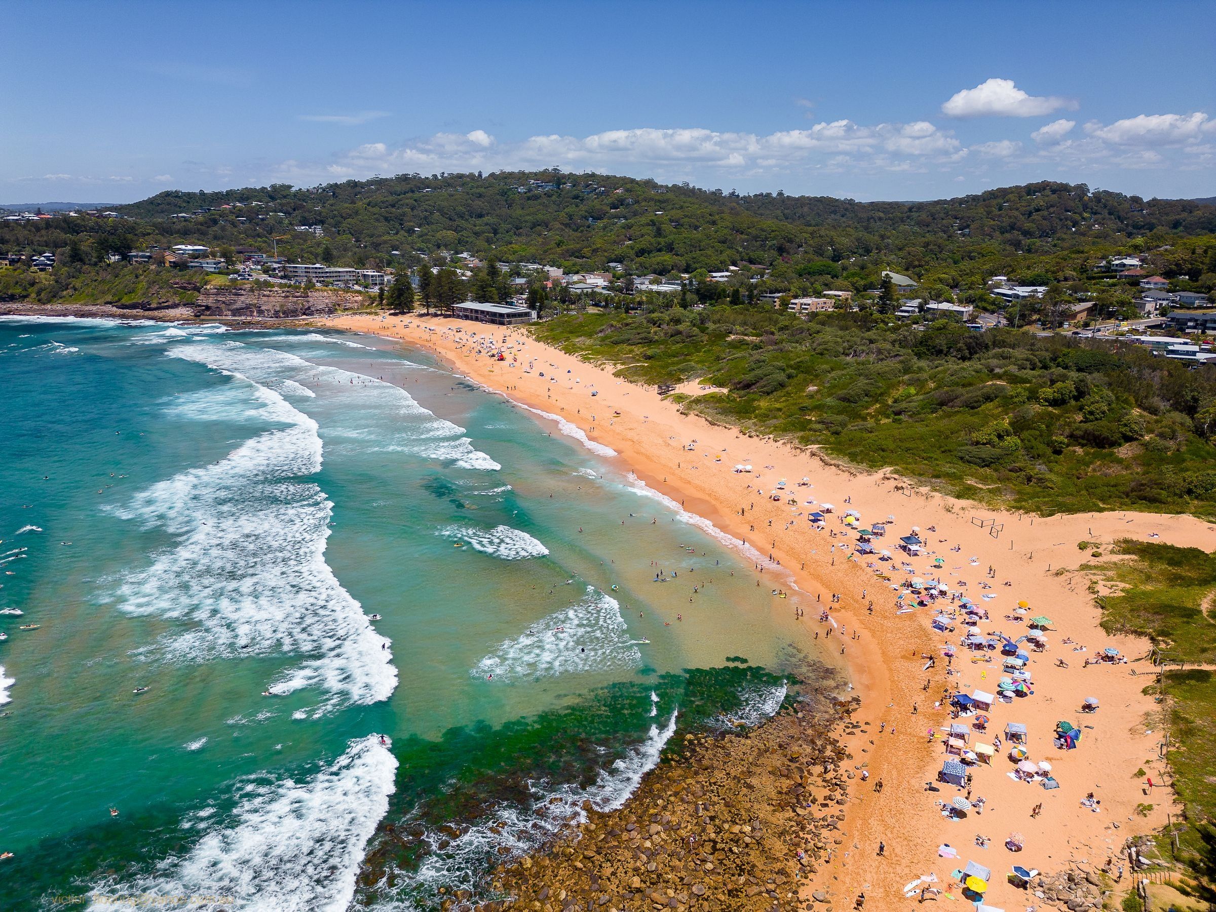 Avalon Beach from above on a sunny day, surf rolling onto the orange sand