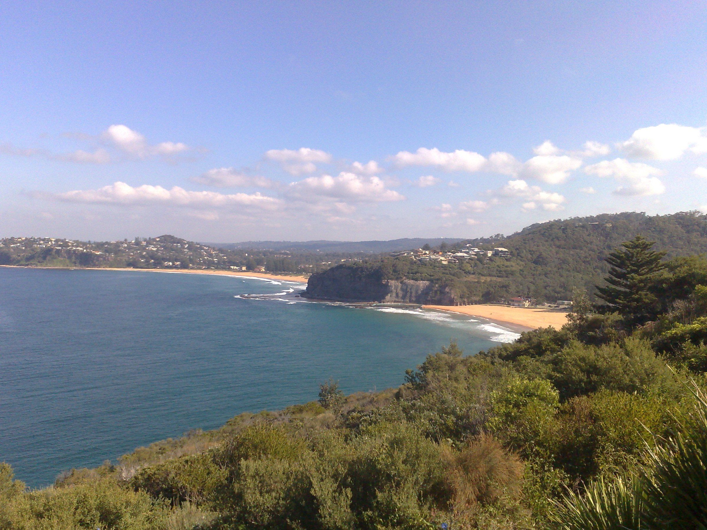 The coast south from the headland road above Bilgola: blue water, a sandstone headland and a beach beyond