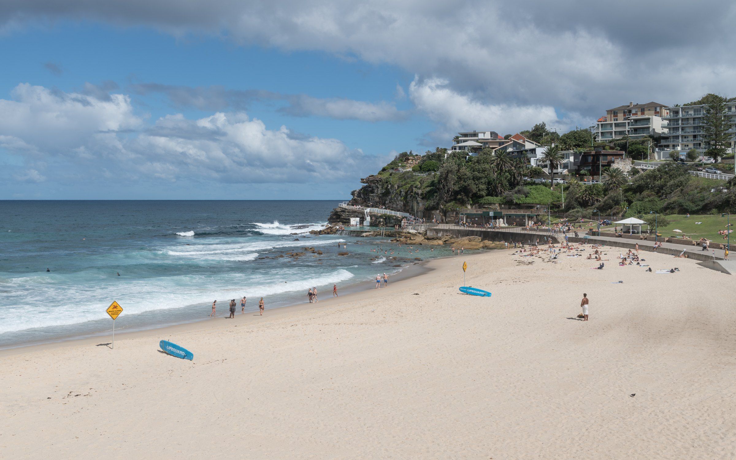 Bronte Beach looking north on a sunny day, the surf club and cliffs at the end of the beach