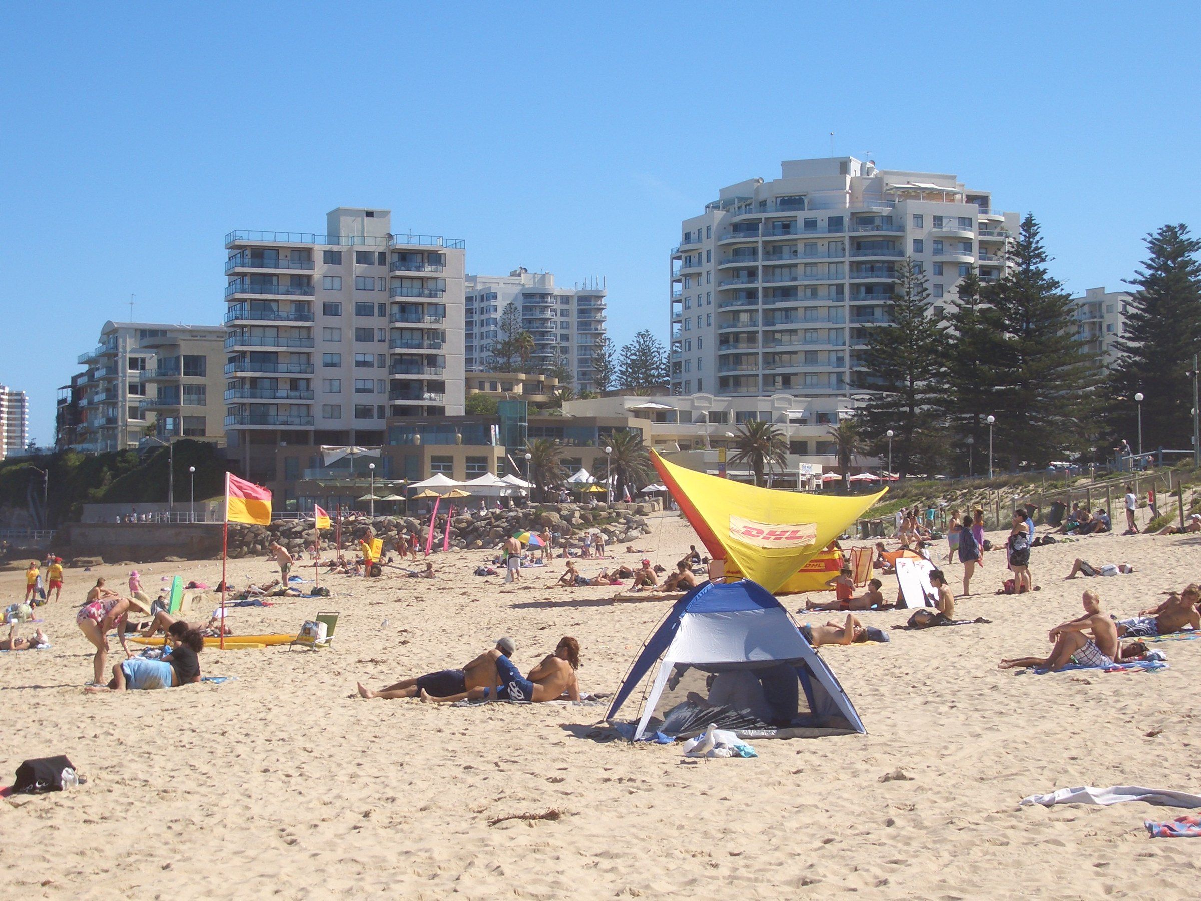 Swimmers and umbrellas on North Cronulla Beach, apartment towers behind