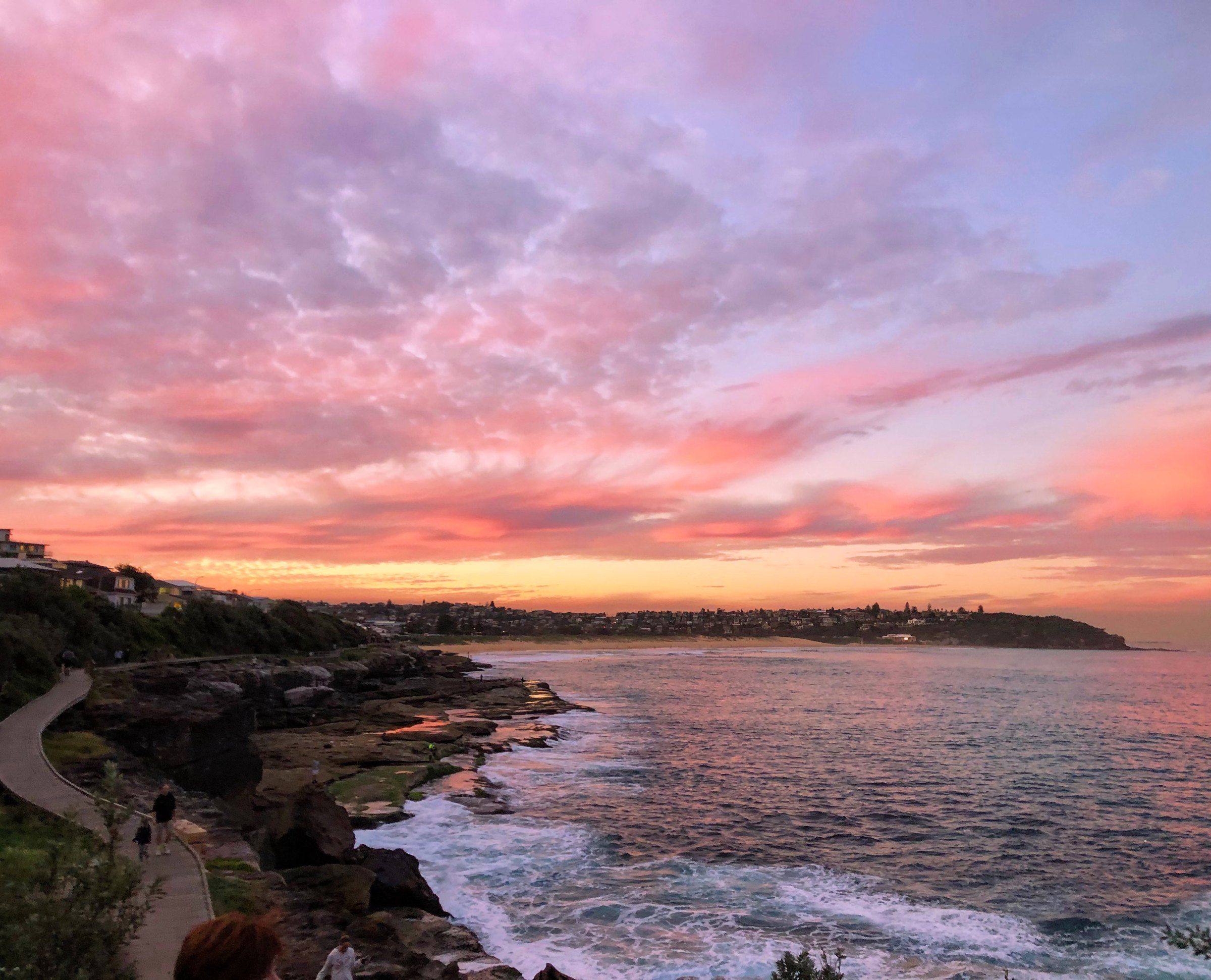 The boardwalk around the rocks at South Curl Curl at sunset, the beach and headland beyond