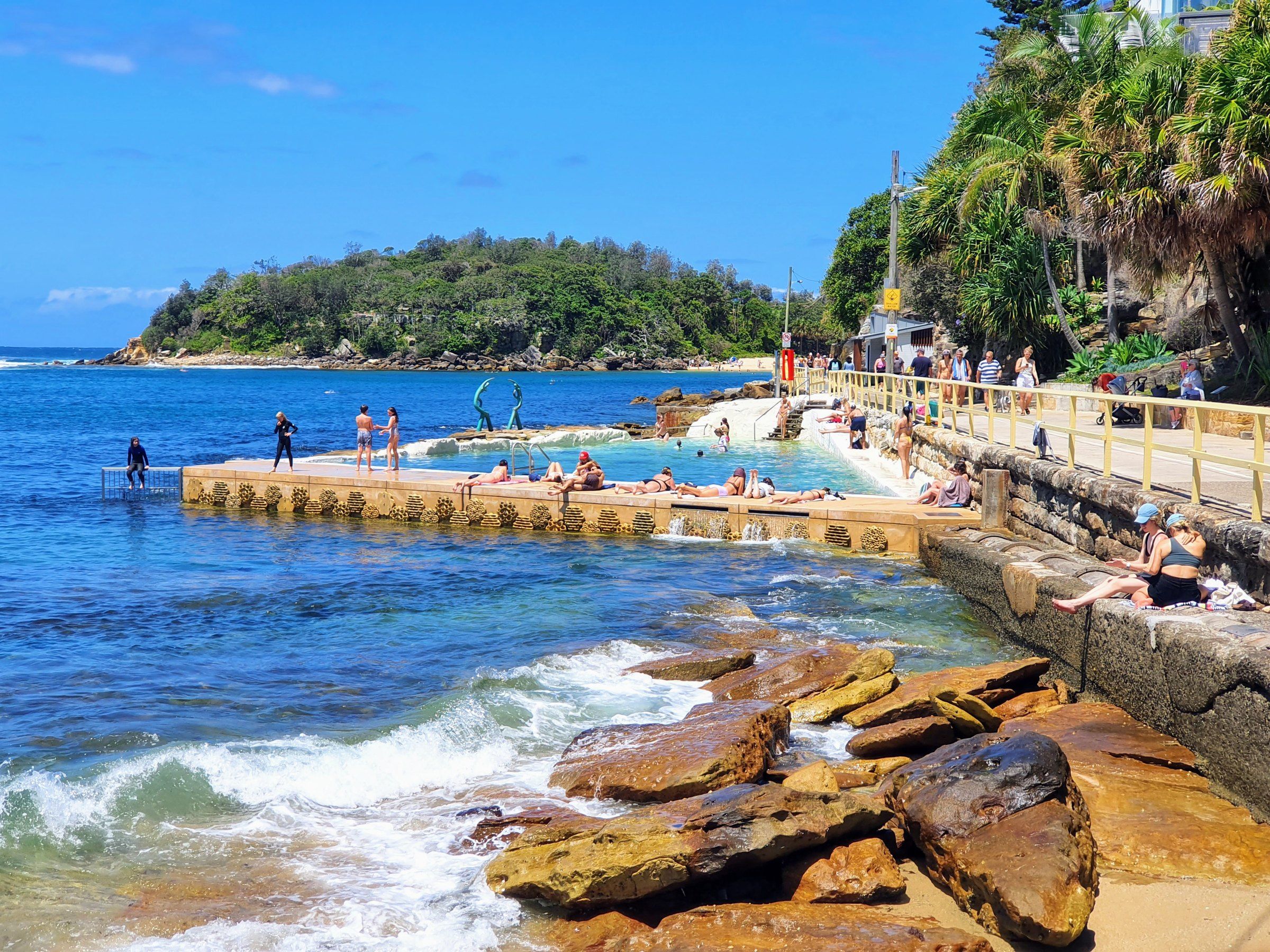 Fairy Bower rock pool and its sea nymph sculpture on the rocks at Manly, swimmers in the pool