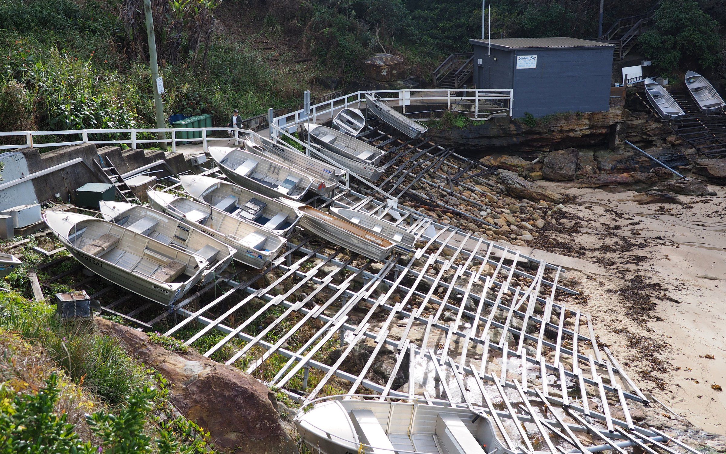 Rows of small fishing boats stored on wooden racks above the sand at Gordons Bay