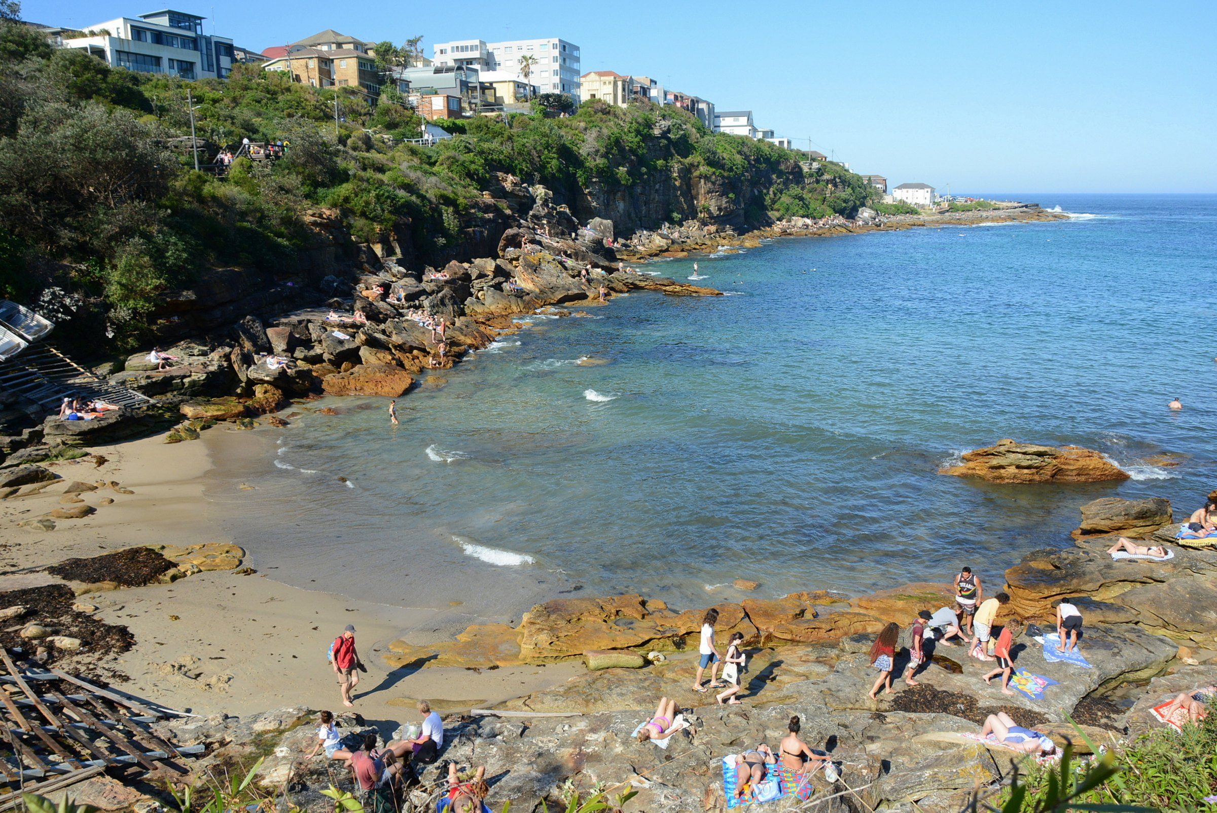 Gordons Bay between Coogee and Clovelly: a small sandy cove with boat racks, bush and sandstone rocks around clear water