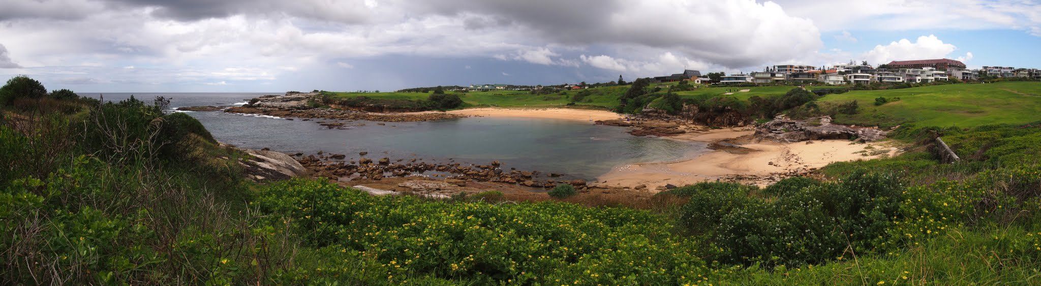 Little Bay from the clifftop, a small sandy cove between rocky headlands
