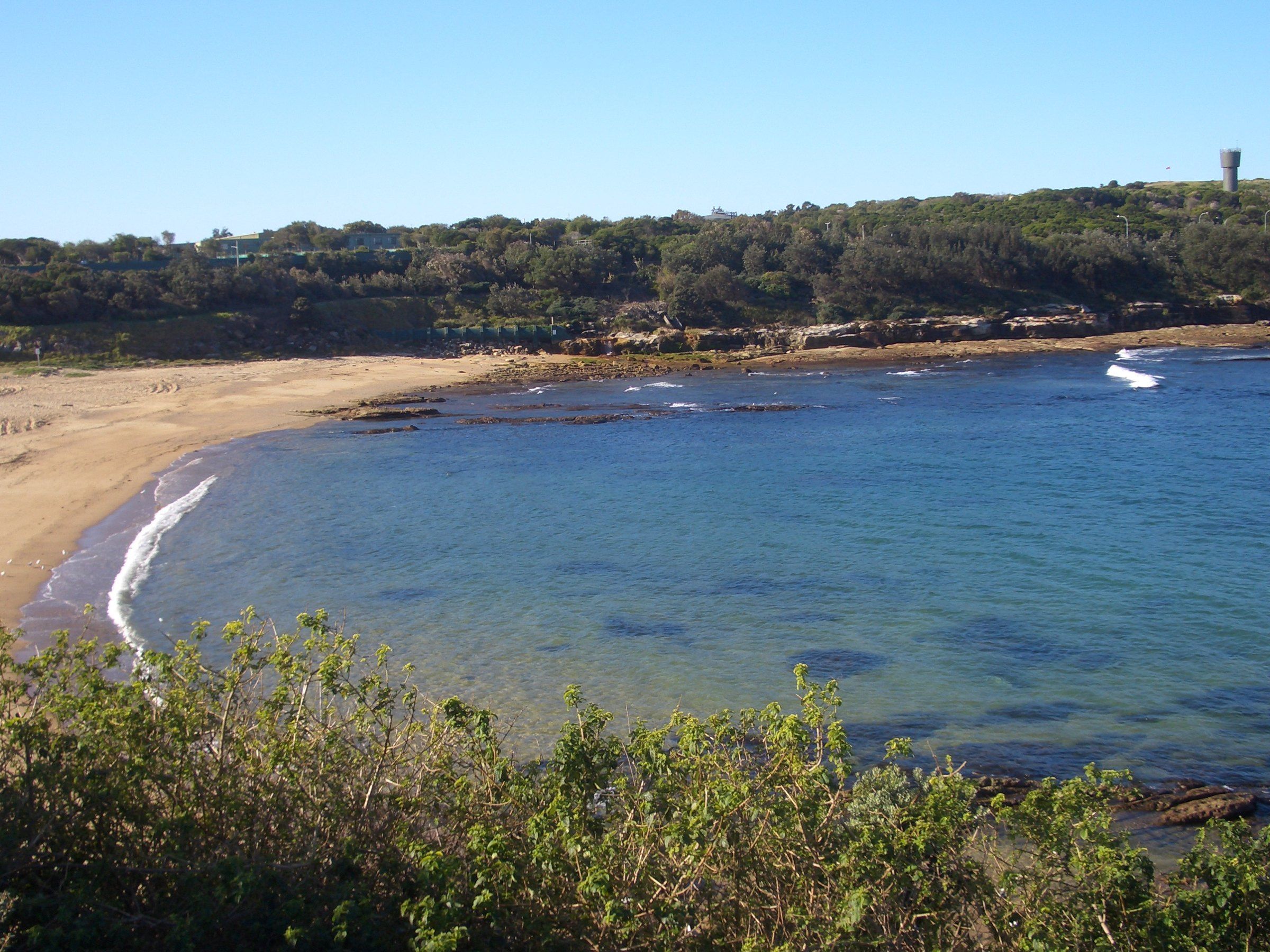 Malabar Beach from the headland, a curve of sand around calm blue water in Long Bay
