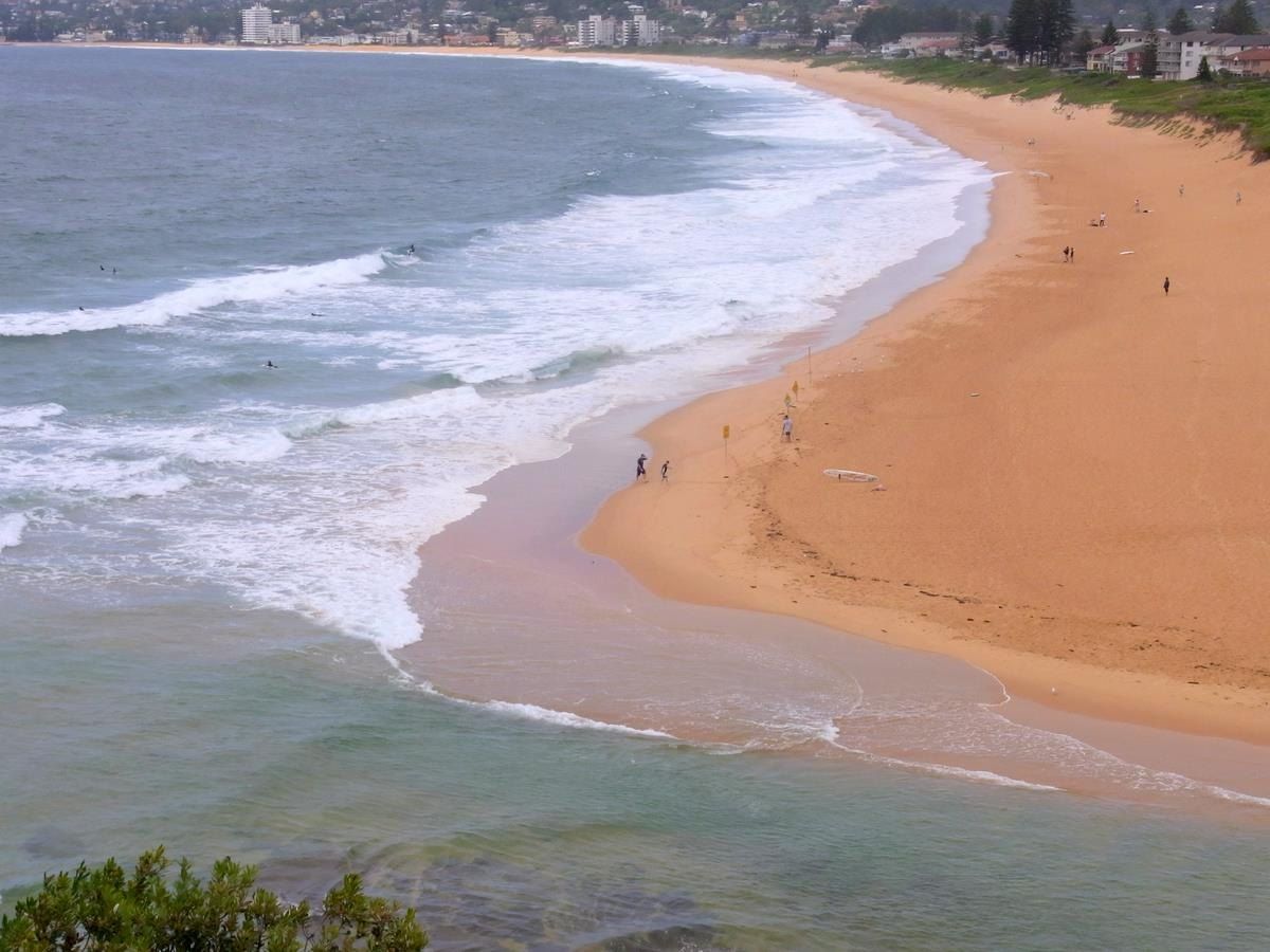 North Narrabeen beach on a sunny day, surf breaking along the sand