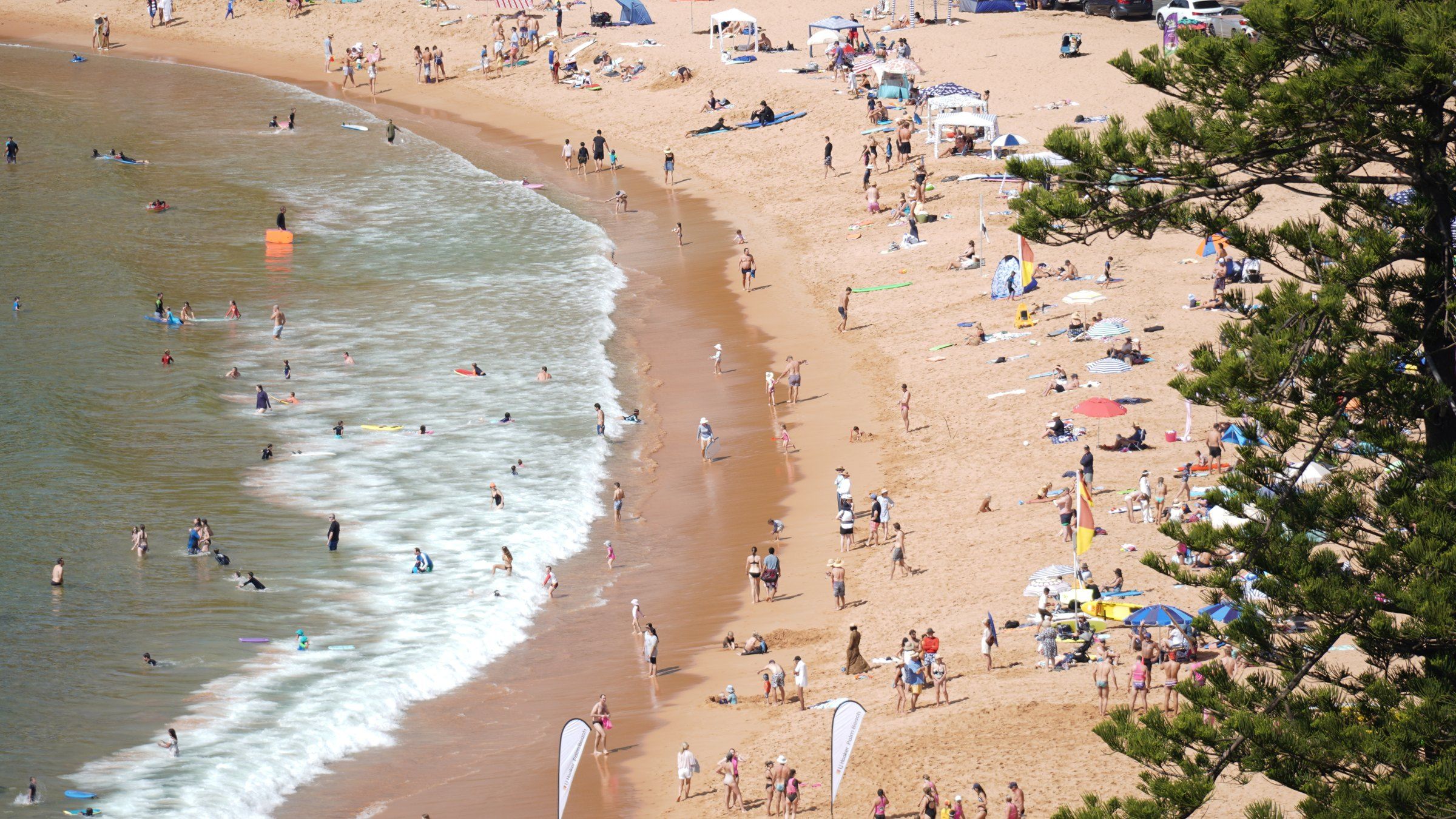 Red and yellow swimming flags on the sand at the south end of Palm Beach, people in the surf