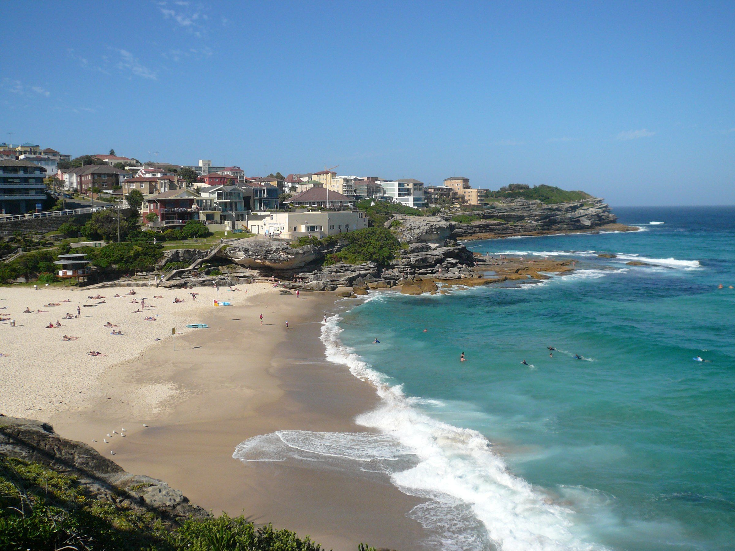 Tamarama Beach from the cliff path on a sunny day, the small curve of sand between rocky headlands