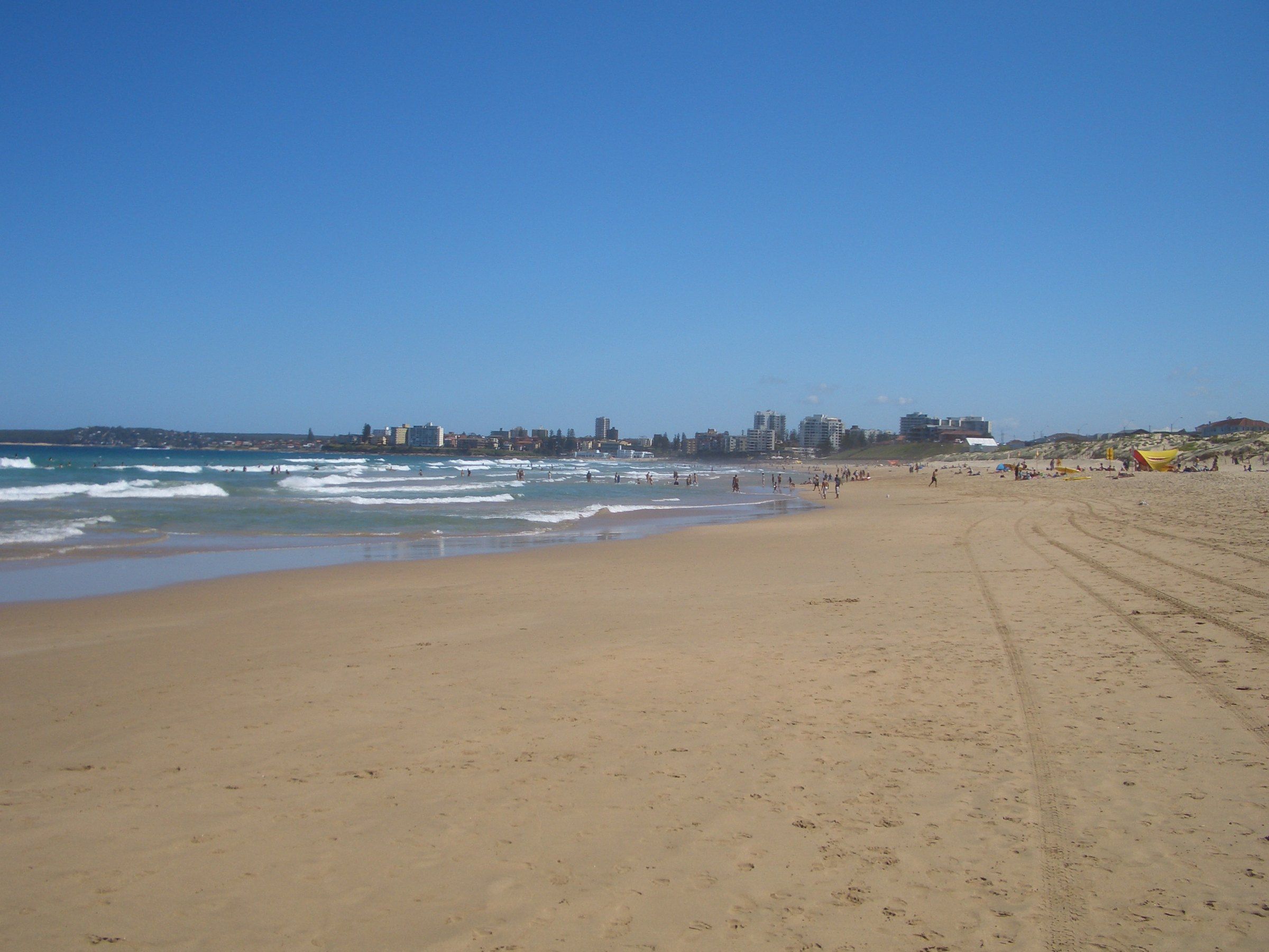 Wanda Beach on a sunny day, the wide sand running south along Bate Bay towards the towers of Cronulla