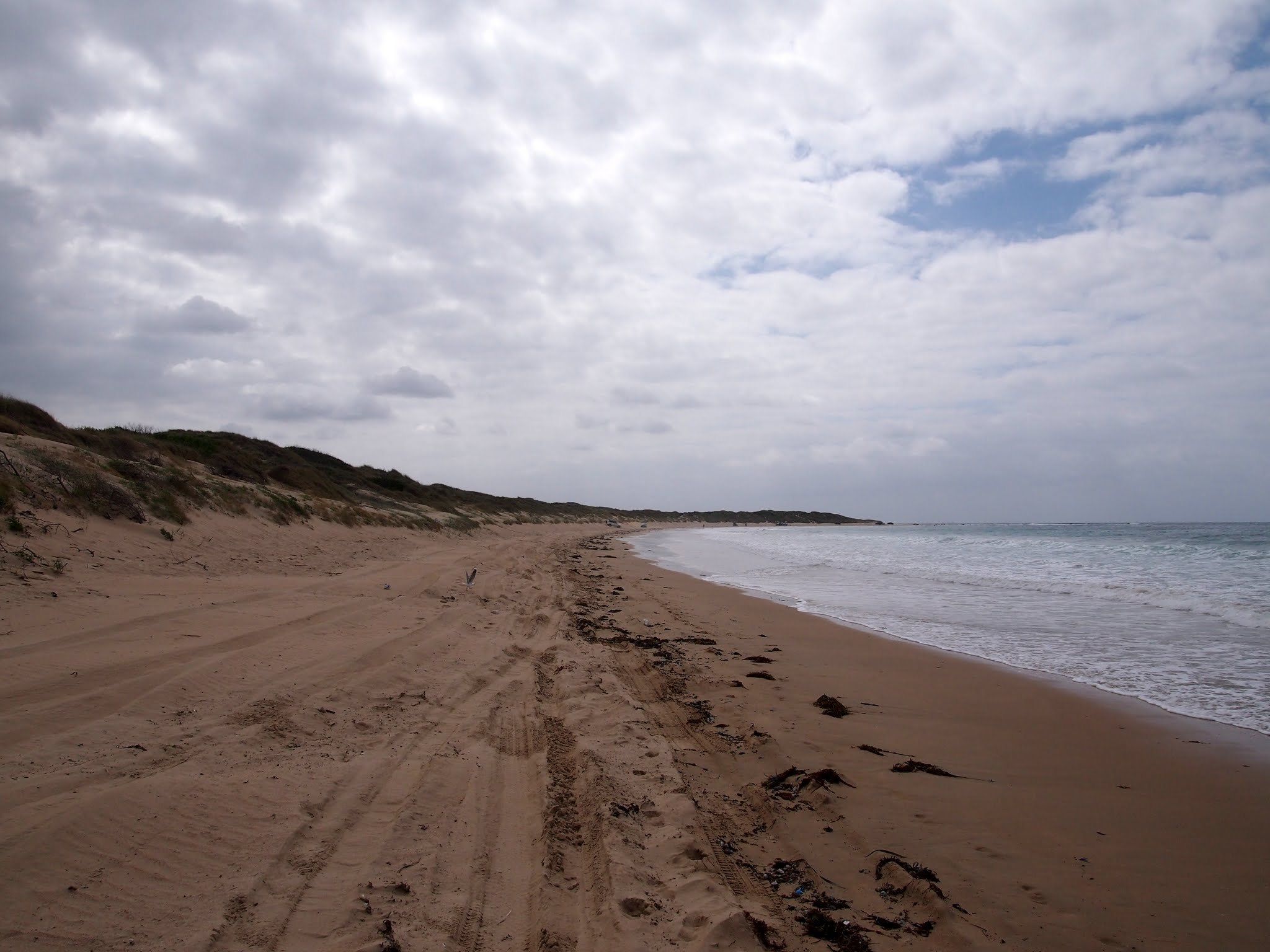 Wanda Beach under cloud, the dunes running along the back of a long empty beach