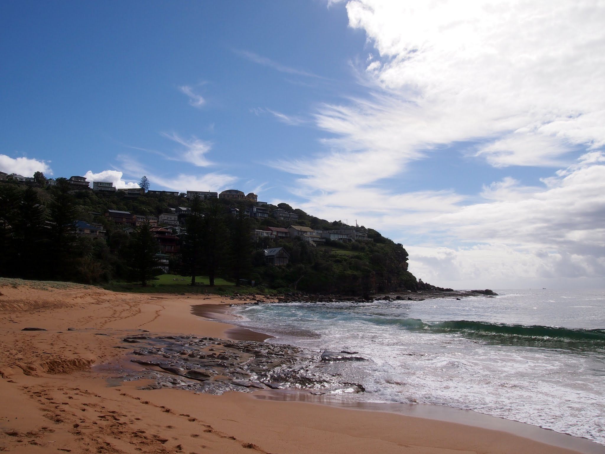 The north end of Whale Beach on a sunny day, the headland and houses above